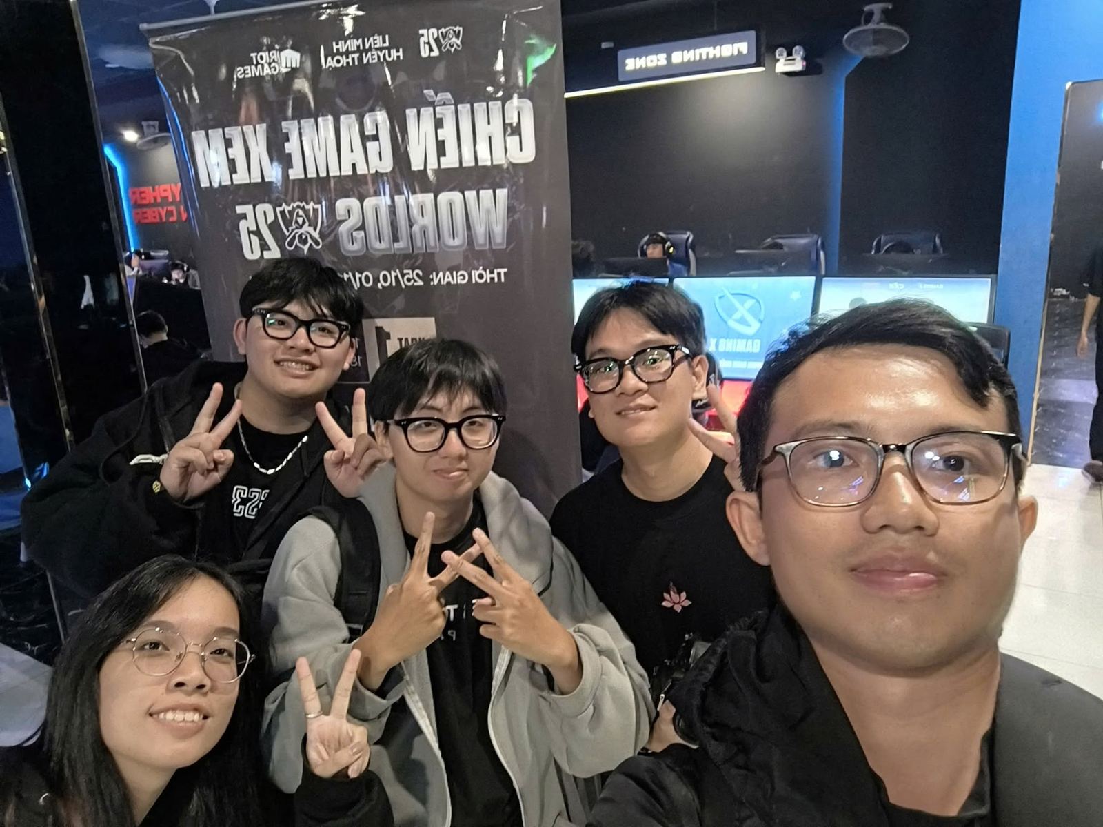 Tom selfie cùng đội esport LMHT trước poster Chiến game xem Worlds 25 tại một điểm xem